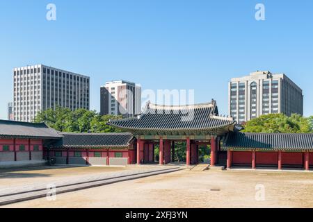 Vue panoramique sur la cour et la porte intérieure Jinseonmun du palais de Changdeokgung à Séoul, Corée du Sud. Les bâtiments modernes sont visibles sur fond de ciel bleu. Banque D'Images
