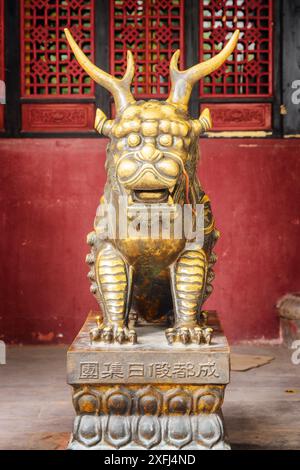 Chengdu, Chine - 25 septembre 2017 : statue du lion gardien chinois mystique sur fond de mur rouge dans le temple de Wenshu (monastère bouddhiste). Banque D'Images