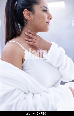 Détente au spa, femme en robe blanche touchant son cou Banque D'Images