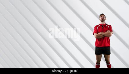 Portrait d'un joueur de rugby masculin caucasien avec les bras croisés debout sur fond blanc rayé Banque D'Images