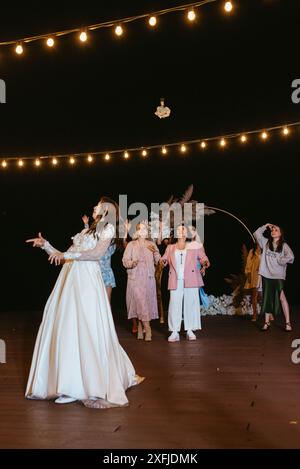 mariée dans une robe blanche jette un bouquet de mariage à ses amies non mariées Banque D'Images