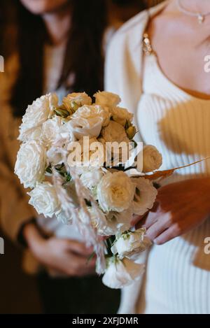 mariée dans une robe blanche jette un bouquet de mariage à ses amies non mariées Banque D'Images