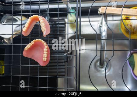 Les fausses dents usagées sèchent au-dessus de l'évier de cuisine Banque D'Images