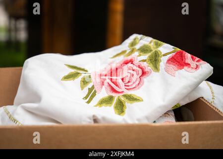 Nappe brodée vintage dans une boîte en carton. Nappe en coton blanc fait à la main avec broderie rose. Mise au point sélective. Banque D'Images