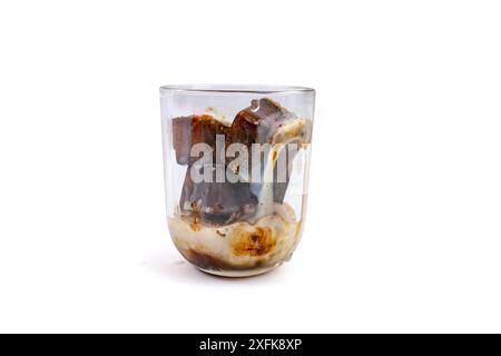 Cubes de café congelé dans un verre transparent versant du lait , isolé sur blanc Banque D'Images