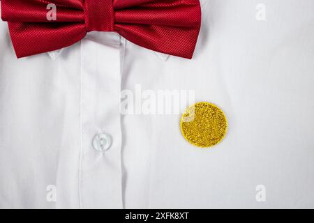 Autocollant de cercle de paillettes dorées sur un coffre d'enfant avec chemise blanche et noeud papillon rouge, concept d'appréciation Banque D'Images