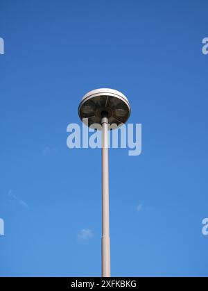 Un lampadaire photographié d'en bas se détache sur un ciel bleu clair, avec une source de lumière LED visible. Idéal comme fond ou texture. Banque D'Images