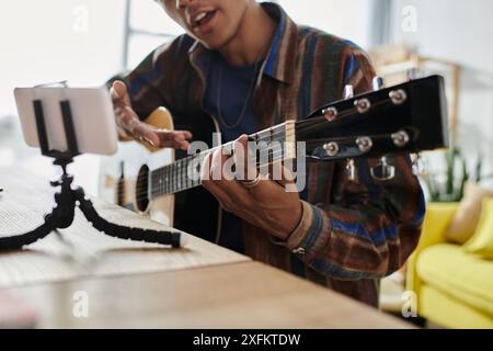 Jeune homme joue passionnément de la guitare acoustique à l'extérieur. Banque D'Images