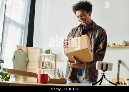 Un jeune homme noir expose une boîte en carton devant un bureau. Banque D'Images