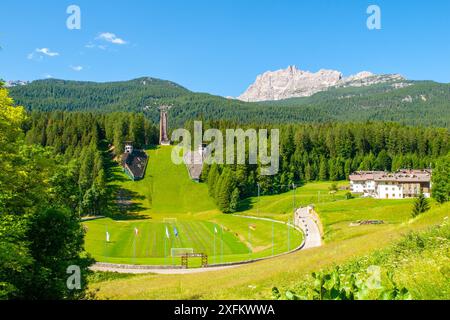 Une vue sur la colline de saut à ski, Trampolino Olimpico Italia, à Cortina d'Ampezzo, en Italie, entourée d'arbres verdoyants et de montagnes. Banque D'Images