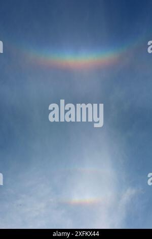 Série d'arcs nuageux provoqués par des cristaux de glace dans les nuages élevés réfractant la lumière du soleil couchant. Surrey, Angleterre, Royaume-Uni, avril. Banque D'Images