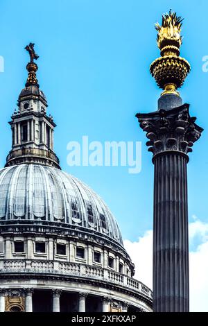 Une vue rapprochée d'une colonne de pierre haute, cannelée, avec un finial doré en forme de flamme. La colonne se dresse devant le dôme de la cathédrale Saint-Paul Banque D'Images