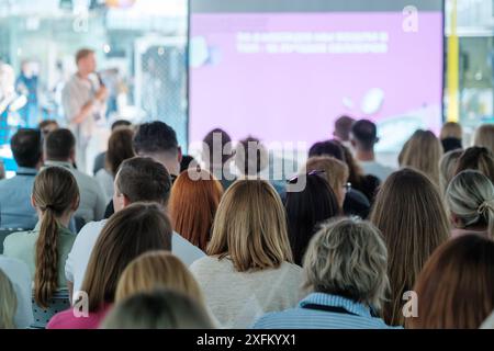 Un large public s'assoit avec attention lorsqu'un conférencier fait une présentation lors d'un séminaire d'entreprise. Le séminaire se déroule dans une salle moderne et bien éclairée. Banque D'Images