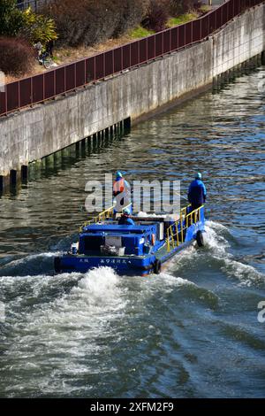 Trois Japonais pilotent un petit bateau de ramassage des ordures dans la rivière Neya Banque D'Images