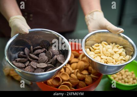 Dame pâtissière montrant des bols avec du chocolat et des pépites laiteuses Banque D'Images