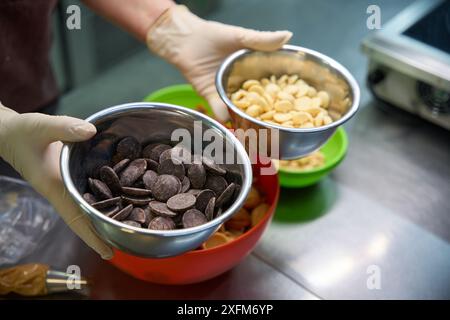 Confiseur tenant deux bols avec des pépites de chocolat blanc et brun Banque D'Images