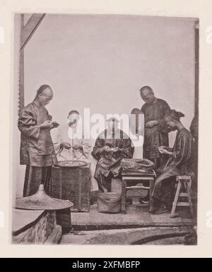 Photo vintage du personnel chinois compradore est schroffing ou test dollars. Illustrations of Qing China, 1875 Schroffing, ou tester et examiner des dollars, est une opération menée par le personnel du compradore pour recevoir le paiement de cargaisons, afin de s'assurer qu'aucune pièce de monnaie contrefaite n'a été introduite. Ces tests sont gérés avec dextérité et rapidité. En transférant les dollars d'un sac à l'autre, deux sont pris à la fois, posés sur le bout des doigts, frappés et sonnés, le ton du métal de base étant facilement détecté. Le fraisage du bord est également examiné, comme le sh chinois Banque D'Images