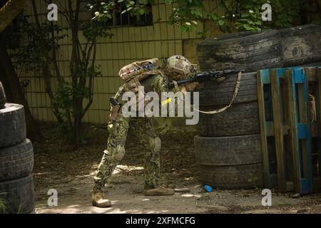 Jeu Airsoft dans la rue près de bâtiments abandonnés, un homme dans un uniforme américain vise une arme Airsoft Banque D'Images