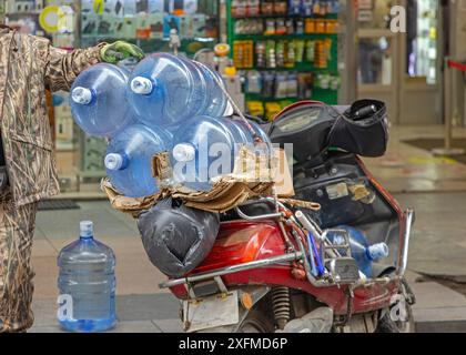 Grande livraison de bouteilles d'eau à Scooter Motorcycle dans la ville Banque D'Images