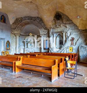 L'intérieur de la cathédrale Simon le Tanner au Caire, en Égypte, avec une niche en pierre sculptée comprenant les vestiges de St. Le corps de Simon et les bancs dans un espace semblable à une grotte Banque D'Images