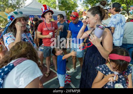 Austin, Texas, États-Unis, 4 juillet 2024. Les voisins socialisent pendant la parade annuelle du quartier de Barton Hills le 4 juillet. Quelques centaines de résidents ont parcouru le parcours du défilé de 1/2 km jusqu'au terrain de jeu de l'école primaire, où ils ont dégusté des biscuits, de la pastèque et de la crème glacée. Crédit : Bob Daemmrich/Alamy Live News Banque D'Images