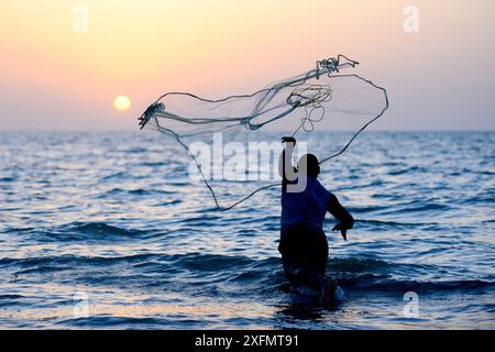 Pêcheur jetant un filet dans la mer de manière traditionnelle au coucher du soleil, île d'Orango, réserve de biosphère de l'UNESCO de Bijagos, Guinée Bissau, février 2015. Banque D'Images