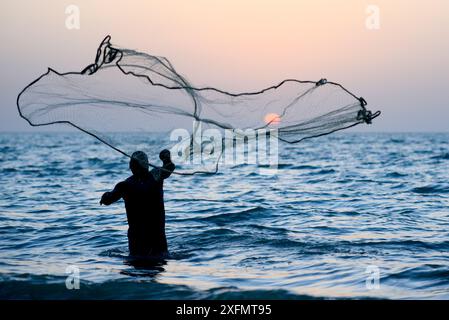 Pêcheur jetant un filet dans la mer de manière traditionnelle au coucher du soleil, île d'Orango, réserve de biosphère de l'UNESCO de Bijagos, Guinée Bissau, février 2015. Banque D'Images