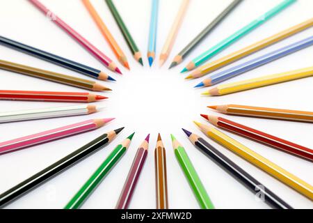 Une collection de crayons de couleur aiguisés sont disposés en cercle sur une surface blanche. Les crayons sont tous de couleurs différentes et sont disposés avec thei Banque D'Images