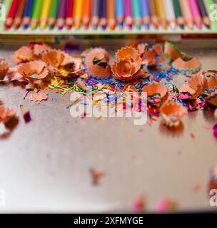 Une pile de copeaux de crayon de couleur sur une table. Les copeaux de crayon sont dispersés dans différentes couleurs, créant une scène vibrante et colorée. Concept de c Banque D'Images