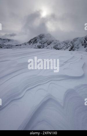 Wind a créé des motifs dans des couches de neige tassée sur Meall Dearg avec Am Bodach en arrière-plan, Aonach Eagach, Glencoe, Écosse, Royaume-Uni, février 2017. Banque D'Images