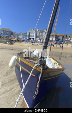 Un bateau de pêche bleu penché sur le sable à marée basse à St Ives, Cornouailles Banque D'Images