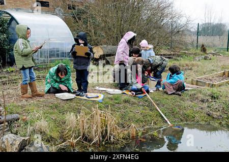 Groupe d'enfants avec leur professeur d'étang plongeant en hiver, Stoke Newington East Reservoir, Now Woodberry Wetlands, London Borough of Hackney, Angleterre, Royaume-Uni, mars 2010. Banque D'Images