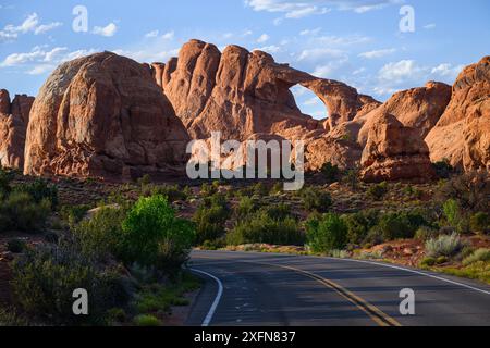 Skyline Arch s'élève au-dessus de la route dans le parc national d'Arches avec des formations rocheuses de grès Banque D'Images