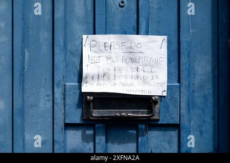 Une note manuscrite amusante collée à une porte d'entrée par le propriétaire de la maison demandant aux gens de ne pas poster de courrier indésirable dans sa boîte aux lettres Banque D'Images