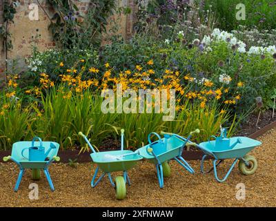 Brouettes à roues pour enfants et arrosoirs dans le projet de jardinage scolaire Angleterre, Royaume-Uni. Banque D'Images