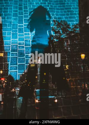 Silhouette double exposition d'une fille marchant le long d'une rue de la ville dans la soirée. Lumière dans les maisons résidentielles. Photographie urbaine créative. Banque D'Images