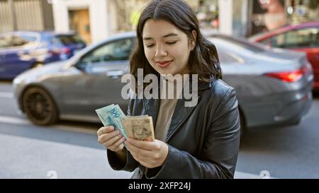 Une jeune femme compte des reais brésiliens dans une rue animée de la ville évoquant la finance urbaine et les thèmes des voyages. Banque D'Images