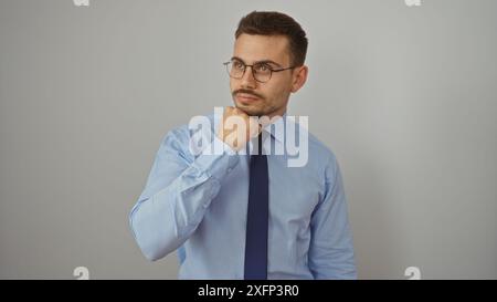 Bel homme hispanique avec une barbe et des lunettes dans une chemise bleue et cravate debout isolé sur un fond blanc dans une pose de portrait. Banque D'Images