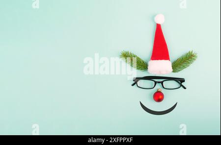 Visage d'un renne avec un nez de boule rouge, des bois de sapin, un chapeau et des lunettes du père noël, carte de vœux de joyeux noël Banque D'Images