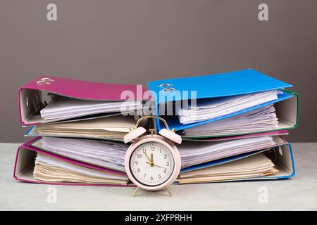 Réveil debout à côté d'une pile de dossiers, burnout, stress et surchargé de travail, pression au travail, échéance Banque D'Images