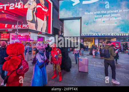 Vue imprenable sur Times Square à New York la nuit, avec des gens vêtus de costumes de personnages variés, de panneaux lumineux et illuminés Banque D'Images