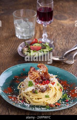 Spaghetti carbonara avec salade sur bois Banque D'Images