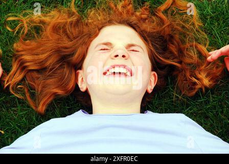 Une jeune fille rit en étant allongée sur l'herbe Banque D'Images