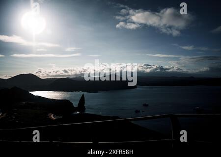 Une vue imprenable sur Pinnacle Rock dans les îles Galapagos, avec le soleil projetant une belle lueur sur l'océan et le paysage volcanique accidenté Banque D'Images