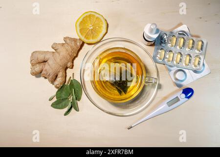 Remèdes maison et médicaments contre le rhume et la grippe tels que le thé à la sauge et au gingembre, le citron, les pilules, le spray nasal et le thermomètre de fièvre, vue de dessus, Banque D'Images