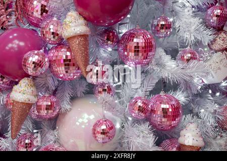 Sapin de Noël orné de décorations roses et blanches, de cônes de crème glacée et d'ornements en matériaux naturels. Une exposition d'arts créatifs avec des œuvres d'art magenta et des bijoux festifs pour l'événement de vacances Banque D'Images