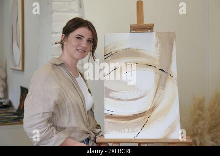 Portrait de femme souriante avec son œuvre d'art dans un studio de dessin Banque D'Images