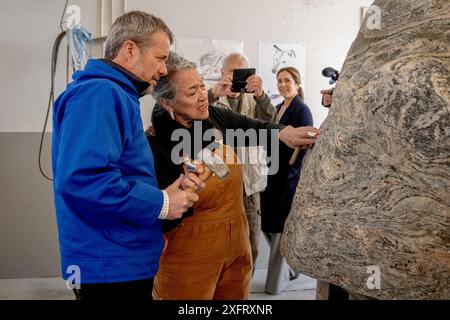 L’artiste aka Høegh regarde le roi Frederik X tenter de sculpter la prochaine pierre commémorative lors d’une visite à un atelier à Nuuk au Groenland, le jeudi 4 juillet 2024. L’atelier travaille sur une pierre commémorative pour l’explorateur polaire Arnarulunnguaq. Seule femme exploratrice polaire, elle participe à la célèbre 5e expédition de Thulé de 1921 à 1924. L'artiste derrière la pierre commémorative est alias Høegh, qui a précédemment réalisé, entre autres, un portrait timbré de la reine Margrethe. Le couple royal visite officiellement le Groenland du 29 juin au 6 juillet 2024. La visite commence dans la baie de Disko et le ro Banque D'Images