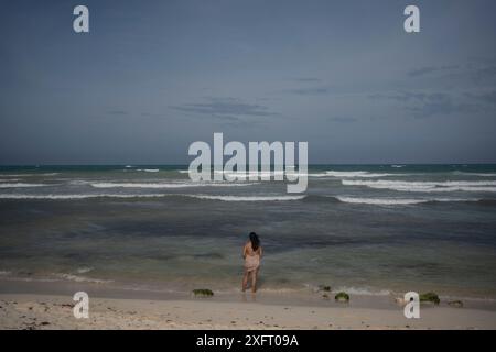 Tulum, Mexique. 04 juillet 2024. Une femme regarde la mer avant l'arrivée de l'ouragan Beryl L'ouragan atlantique devrait atteindre la côte est de la péninsule de Yucatán avec l'ouragan force 1 vendredi soir. Les experts s'attendent à de forts vents et des précipitations ainsi qu'à de dangereuses ondes de tempête. Crédit : Felix Marquez/dpa/Alamy Live News Banque D'Images