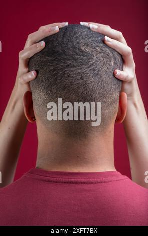 les mains d'une femme blanche tiennent doucement la tête rasée d'un homme noir. Cette scène représente l’inclusivité, la fluidité du genre, le non binarisme, l’acceptation LGBTQIA+ Banque D'Images